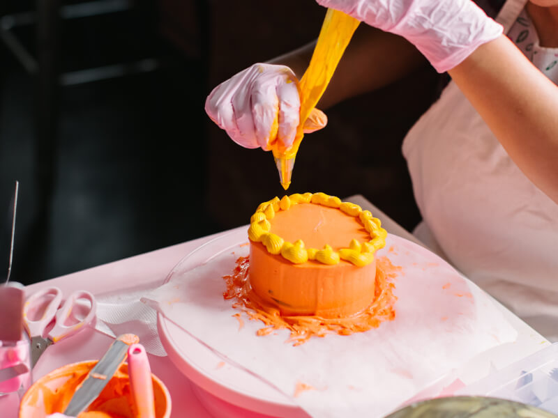 Woman icing an orange cake